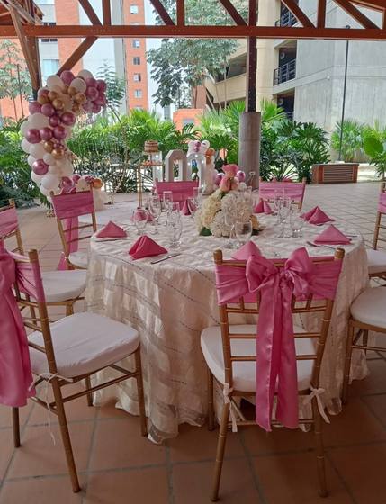 Mesa de evento en tonos rosa con sillas chiavari