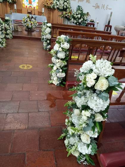 Arreglos florales blancos en bancas de iglesia