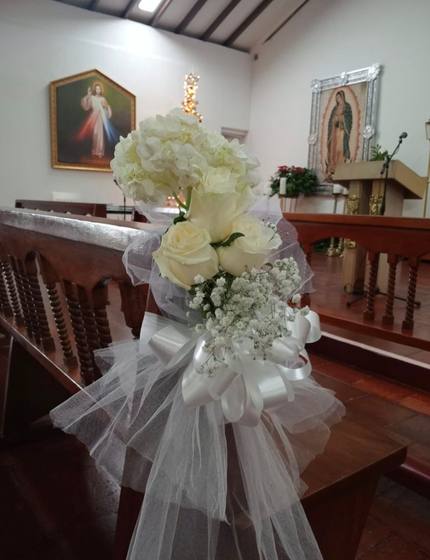 Ramo de rosas blancas con tul en banca de iglesia